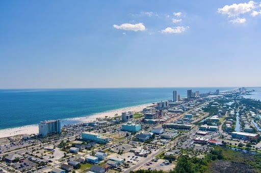 An aerial view of Gulf Shores, Alabama, showcasing the coastline with beachfront buildings and the Gulf of Mexico.